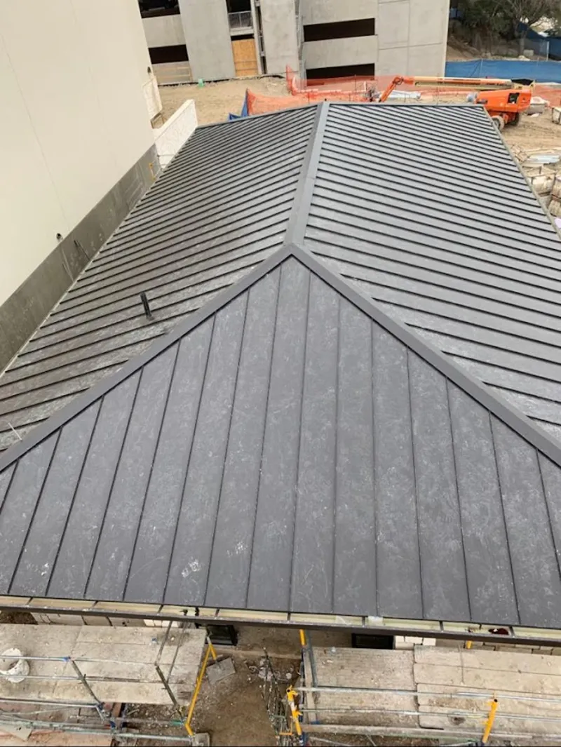 Commercial metal roof construction with crane equipment in Kingston